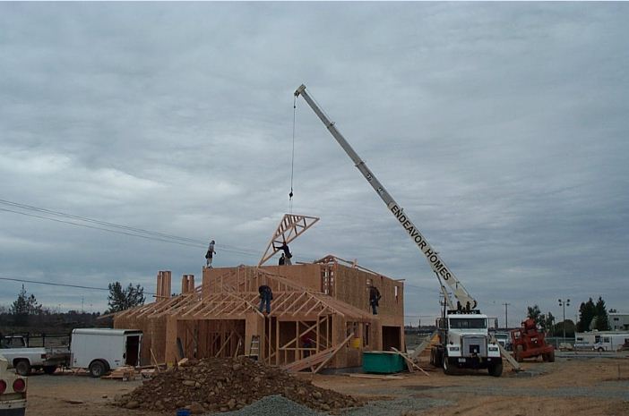 The Endeavor Homes boom truck setting roof trusse on the top plate of a commercial building